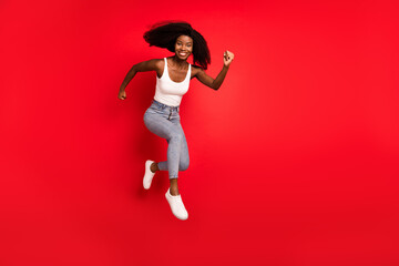 Full length profile side photo of young afro girl happy positive smile jump up go walk run hurry sale isolated over red color background