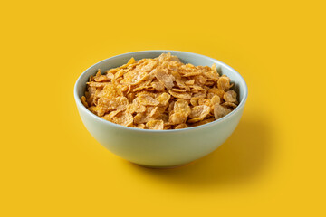 Corn flakes in a blue bowl on yellow background