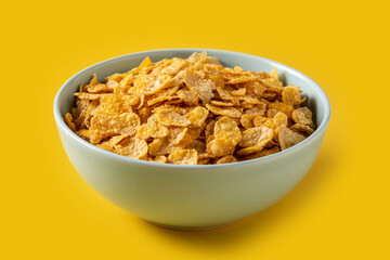 Corn flakes in a blue bowl on yellow background