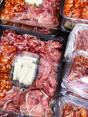 Plastic container with charcuterie Board. Assorted meat and cheese. Ready to serve and eat. On...