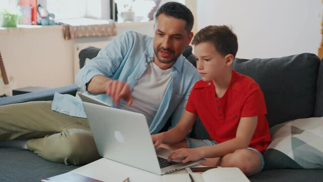 Happy father helping his son with homework while homeschooling in the living room