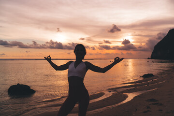 Cheerful female in activewear doing Gyana mudra on beach