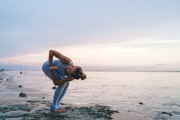 Flexible woman doing yoga on coast