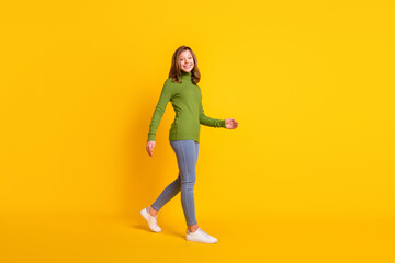 Full length body size photo girl walking forward in casual clothes smiling isolated vivid yellow color background