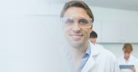 Composition of smiling caucasian male scientist wearing protective glasses with copy space