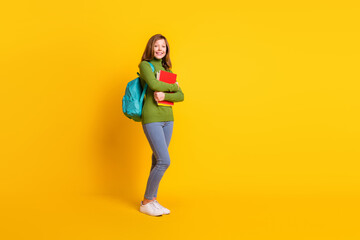 Fototapeta na wymiar Full length body size photo girl keeping book pile wearing backpack smiling isolated vivid yellow color background