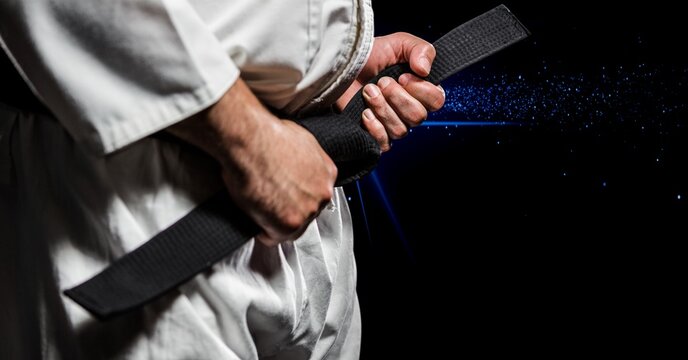 Composition of midsection of caucasian male martial artist with black belt over smoke on black