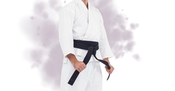 Composition of midsection of caucasian male martial artist with black belt over smoke on white