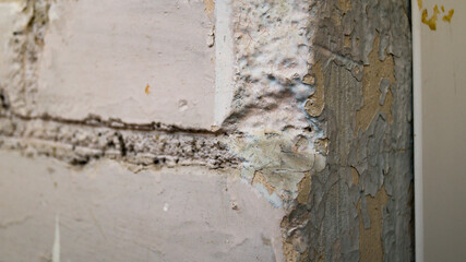 A peeled side of plaster against an old brick wall. The old finish is falling off the wall. The concept of repair, construction, decoration.