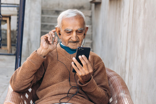 Portrait of happy old Indian man talking on videocall with family with vivid expressions. Concept of modern lifestyle of elder people with help of technology