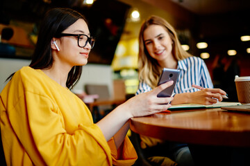 Happy female friends watching video on smartphone