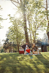 Happy young mother and father with little boy smiling while having picnic outdoors