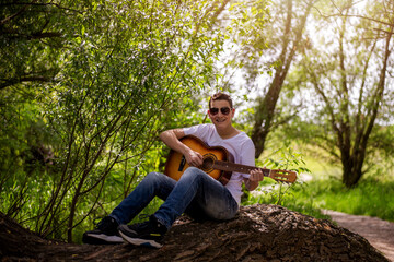 Naklejka na ściany i meble Portrait of beautiful teenager playing guitar outside