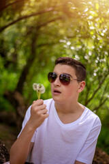 Teen boy blowing dandelion seeds