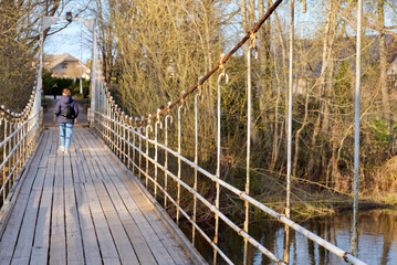 Old hanging footbridge across a small river in Estonia at spring