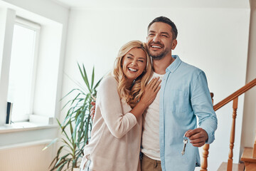 Young beautiful couple in casual wear smiling while holding  keys from new home