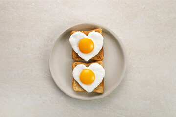 Heart shaped egg in tosted slice of rye bread on ceramic plate. Love breakfast design. Healthy...