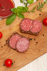 Smoked sausage, ketchup and greens on a wooden board. Top view