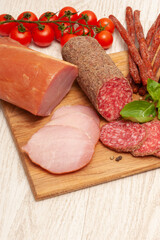 Different types of sausages with tomatoes and herbs on a wooden board. Top view