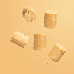 Sweet Brazilian peanut called Paçoca falling down on orange background. From June Celebration