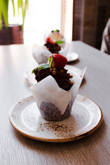 chocolate cupcake decorated with strawberries in a cafe