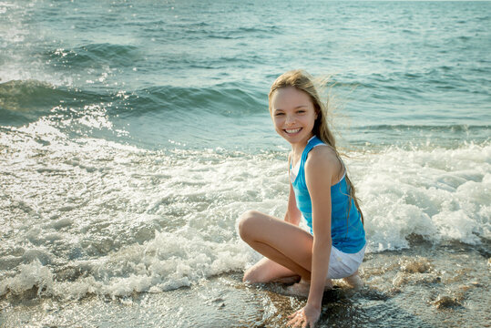 Portrait of beautiful little girl is playing in sea waves. Kid and vacation, tourist destination
