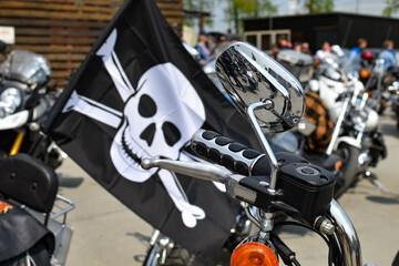 black flag with skull and bones attached to motorcycle. motorcycle steering wheel with rear-view...