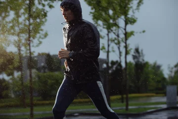 Gordijnen Man jogging under rain, flash light © antgor
