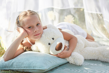 Little girl in white chiffon tent with toy