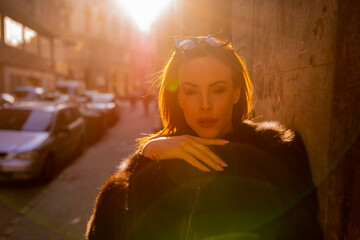 Beautiful young woman posing in the backlight on the street