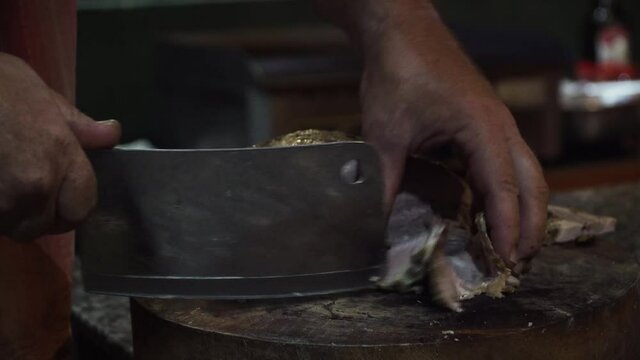 Indian food court in Vietnam. Person slicing meat using a meat cleaver. Close up locked off shot.