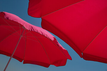 Close up of two red parasols against clear blue sky. Copy space.