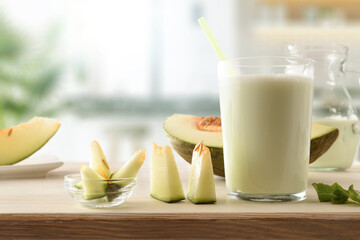 Glass with melon milk shake on bench in kitchen front