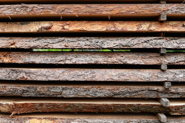 Unedged board of soft wood stacked in the open air. Selective focus.