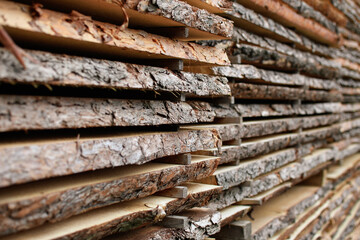 Unedged board of soft wood stacked in the open air. Selective focus.
