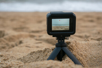 Compact action camera capturing beach scene, isolated over the outside background