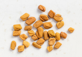 several whole fenugreek seeds close up on gray