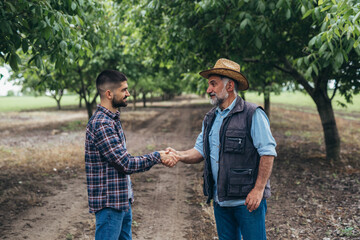 ranchers handshake in walnut orchard