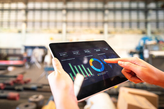 Stock Management Concept, Action Of People Using Smartphone Or Tablet To Generate The Goods Exporting Report, With Blurred Background Of Warehouse.