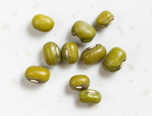 several raw green mung beans close up on gray