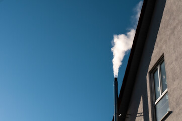a smoking chimney emitting white clouds to blue sky