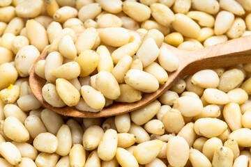 wood spoon with shelled pine nuts on pile of nuts