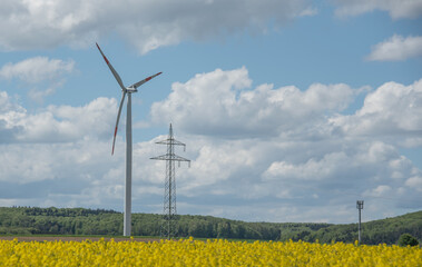 a wind turbine and an electricity pylon in rural landscape