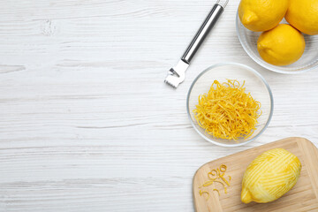 Flat lay composition with fresh lemon zest on white wooden table. Space for text