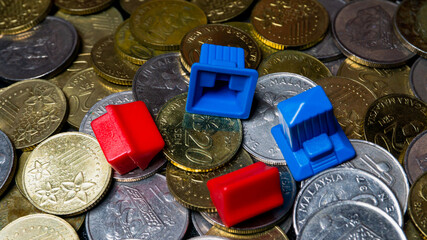 Two blue and red mini building miniature on a collection of gold and silver Malaysian 20 sen coin. © Aiman Khair