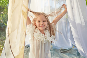 Fototapeta na wymiar Little girl in white chiffon tent