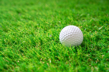 Golf ball on the green artificial grass. Background with copy space.