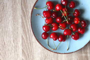 Blue plate filled with fresh cherries. Flat lay.