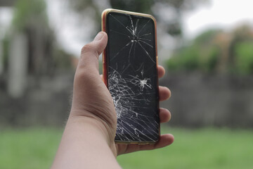 Hand holding broken cell phone lcd glass cracked and broken