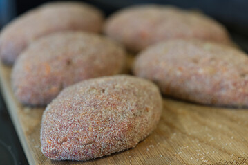 Raw cutlets made of ground beef meat on a rustic chopping board. homemade cutlets